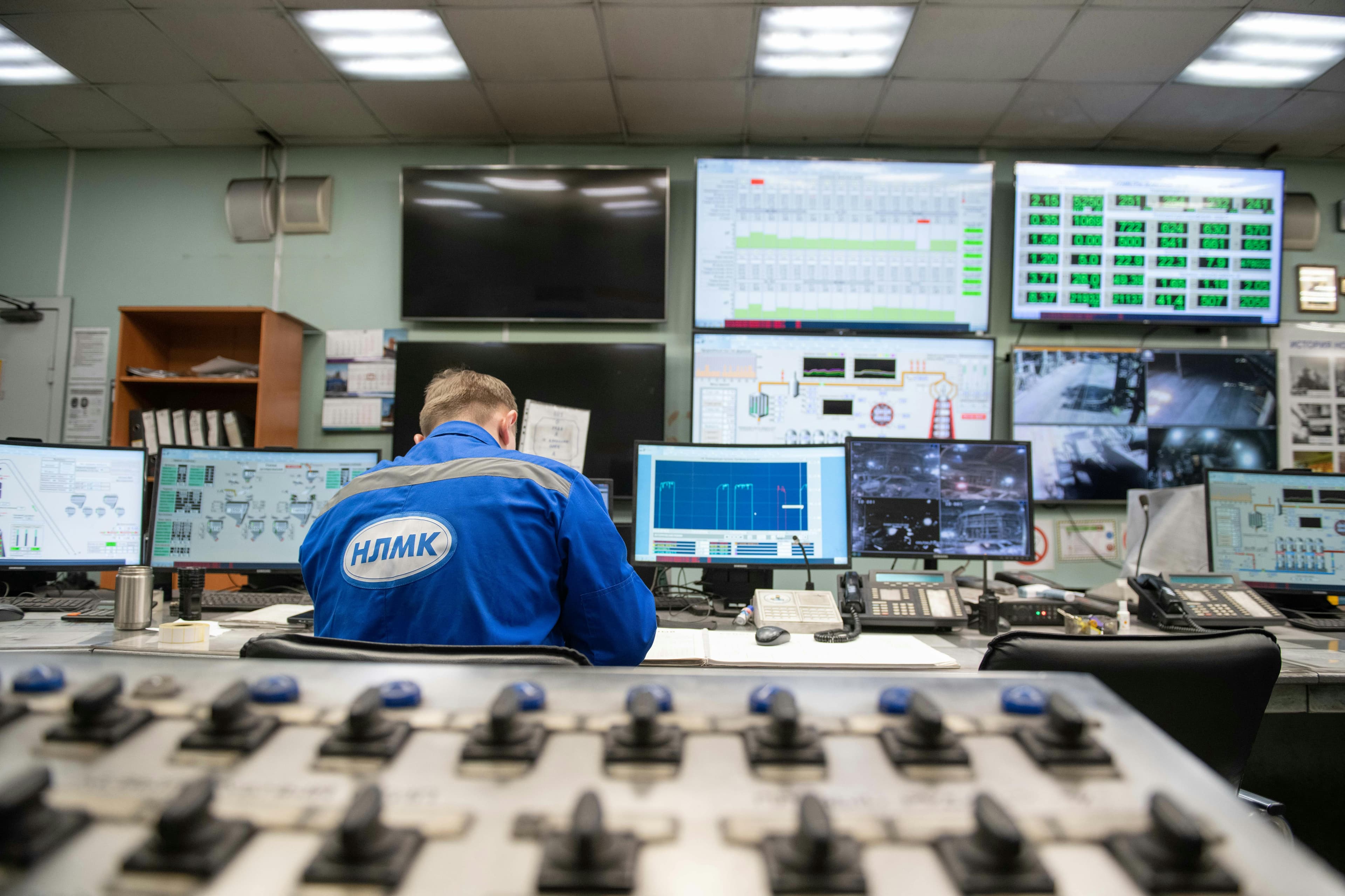 An engineer monitoring multiple operational screens in a control room.
