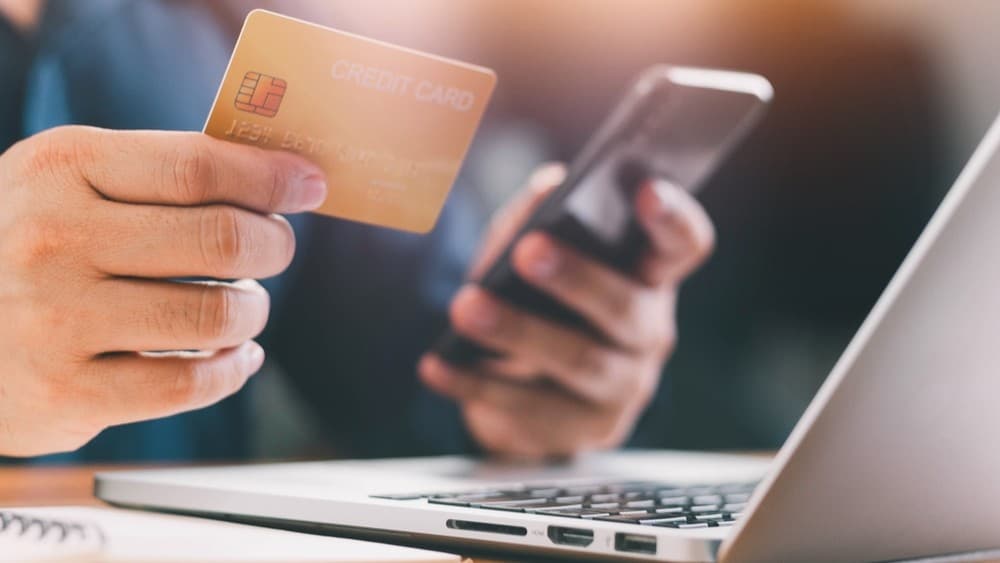 Hands using a secure payment device over a laptop.